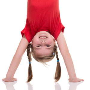little girl standing on her hand isolated on white